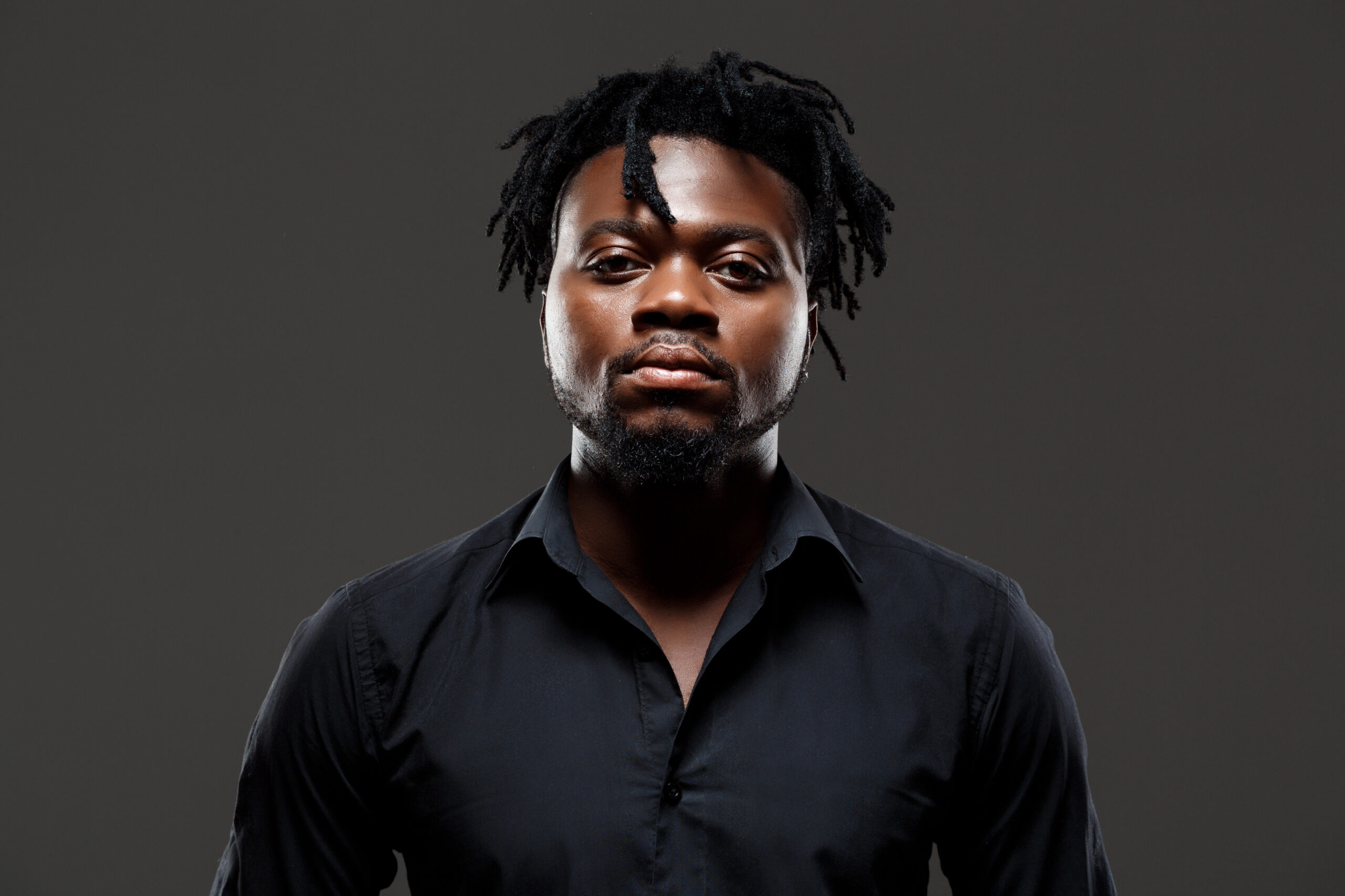 young successful african businessman posing over dark background.